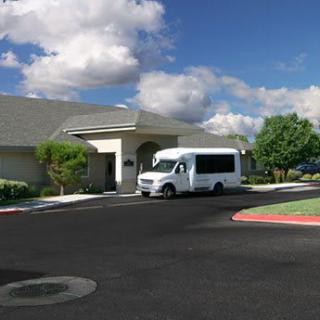 A white van parked in front of a building under a partly cloudy sky.