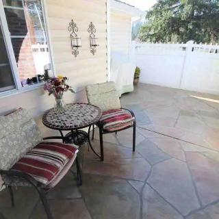 A cozy patio area featuring a small table with two chairs, adorned with a vase of flowers, set on stone flooring.