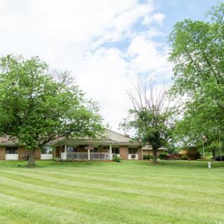A beautiful house surrounded by a well-maintained lawn and trees under a cloudy sky.