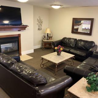 A cozy living room with leather sofas, a fireplace, and a mounted TV.