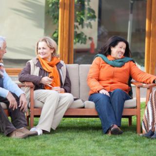 A group of people sitting on a garden bench enjoying a conversation.