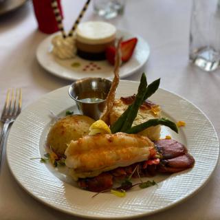 A gourmet meal featuring steak and lobster, elegantly plated with side dishes.