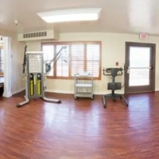A small gym with exercise equipment and wooden flooring.