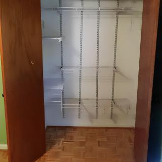 An empty closet with built-in shelves and hanging rods.