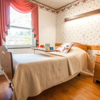 A cozy hospital room with a bed and window featuring elegant curtains.