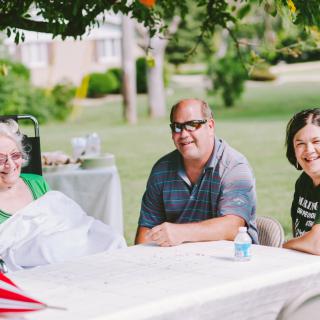 A group of people enjoying a picnic outdoors under the shade of trees.