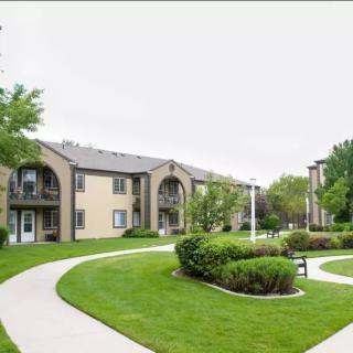 A well-maintained apartment complex featuring lush greenery and paved walkways.