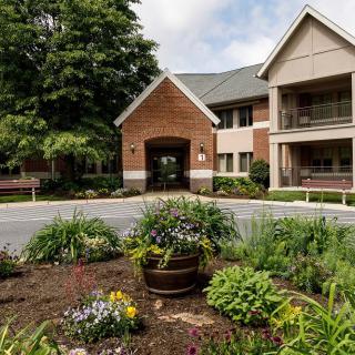 A landscaped entrance to a residential building with flowers and greenery.