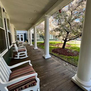 A charming porch with rocking chairs, surrounded by columns and a lush garden.