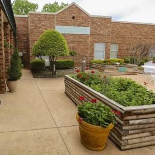 Outdoor garden area with planter boxes and a brick building in the background.