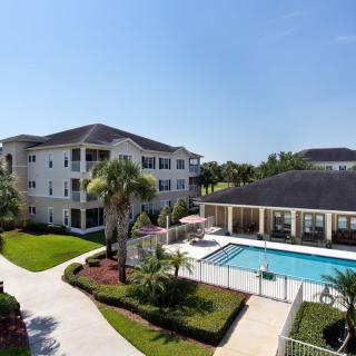 A view of an apartment complex with a swimming pool surrounded by well-maintained gardens.