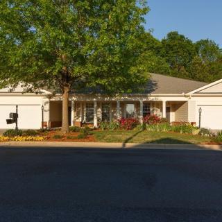 A suburban house with a well-maintained front yard and a large tree.