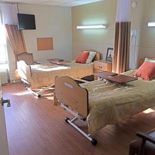 A shared patient room in a healthcare facility, featuring two beds with comfortable bedding and a warm ambiance.
