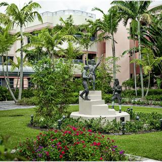 A beautifully landscaped garden featuring statues surrounded by lush greenery and palm trees.