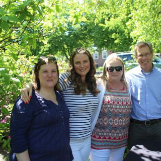 A group of four people standing together outdoors on a sunny day.