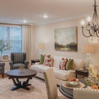 A cozy and elegantly decorated living room featuring a comfortable sofa, armchairs, a round coffee table, and a chandelier.