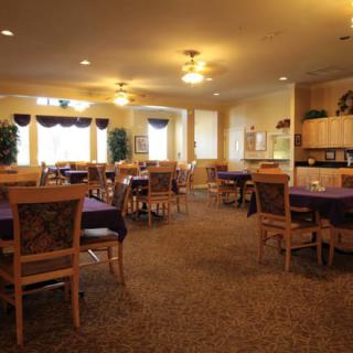 A spacious dining room with neatly arranged tables and chairs, warmly lit by ceiling lights.