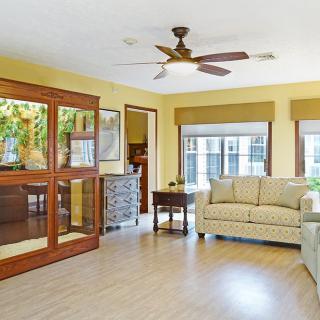 A bright living room with a sofa, ceiling fan, and large windows.