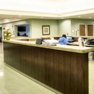 A modern hospital reception desk with a staff member working at a computer.