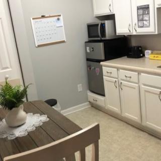 A small kitchen with a dining table, chairs, microwave, and white cabinets.