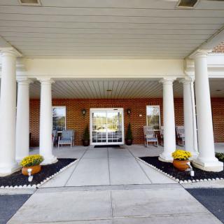 A welcoming entrance with white columns and potted flowers.
