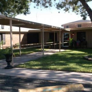 A building entrance with a covered walkway and a grassy lawn.