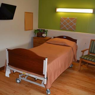 A well-furnished hospital room featuring a single bed and a chair.