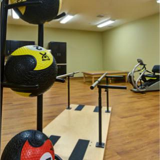 A gym space featuring a rack of medicine balls and exercise equipment.
