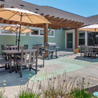 A sunny outdoor patio with tables, chairs, and umbrellas next to a building.