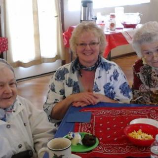A group of smiling seniors sitting together at a table with food.