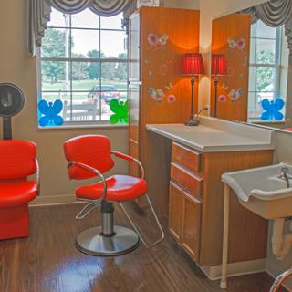 A cozy hair salon interior with a red chair, mirror, and decorative window.