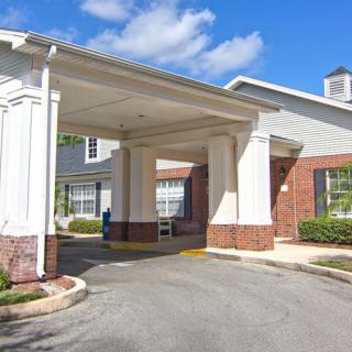 Entrance of a building with brick and white architecture under a clear blue sky.
