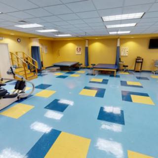A therapy or rehabilitation gym with colorful tiled flooring and various exercise equipment.