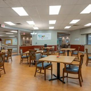 An empty dining area with neatly arranged tables and chairs under bright lighting.