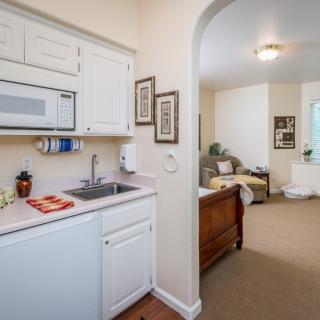 A cozy apartment interior featuring a small kitchen area and a connected living room.
