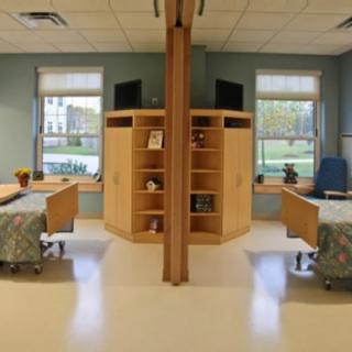 A modern hospital room with two patient beds separated by a partition.