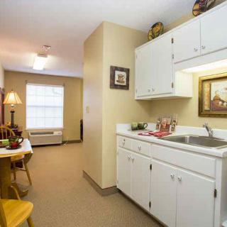 A cozy apartment kitchenette with white cabinets and a small dining area.
