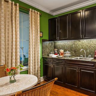 A cozy kitchen with dark cabinets and green walls, featuring a small dining table with flowers.