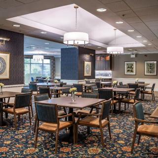 Cozy restaurant dining area with wooden tables and chairs, warm lighting, and decorative elements.