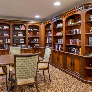 A cozy library with wooden bookshelves and a table surrounded by chairs.