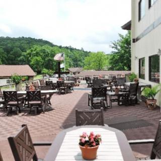 A spacious outdoor patio with tables and chairs, surrounded by lush greenery and a scenic view.