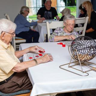 Elderly individuals playing bingo together in a community setting.