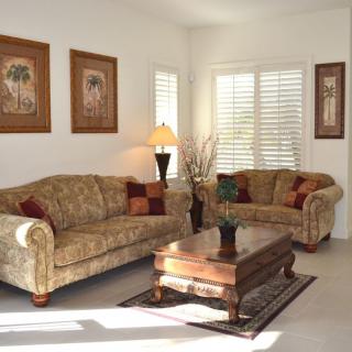 A cozy living room featuring a patterned sofa and loveseat, a wooden coffee table, and framed artwork on the walls.