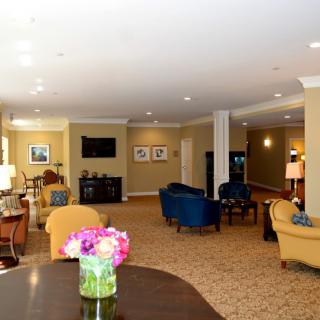 A spacious and well-decorated living room with comfortable seating and a vase of flowers on the table.