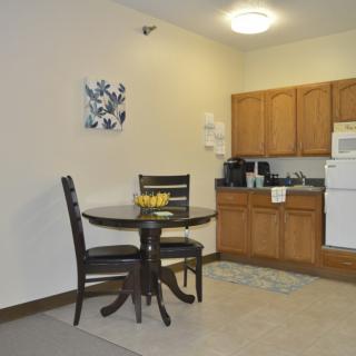 A small kitchen area with wooden cabinets and a dining table set.