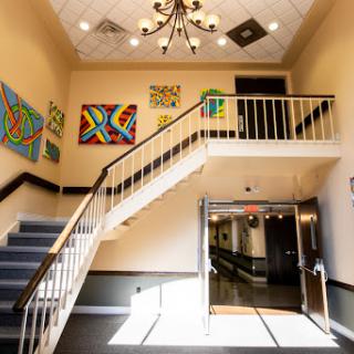 A well-lit staircase featuring colorful artwork on the walls, leading to an inviting hallway.