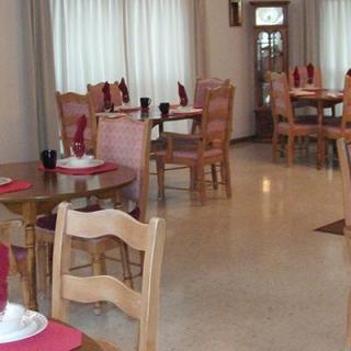 An empty restaurant dining area with neatly arranged tables and wooden chairs.