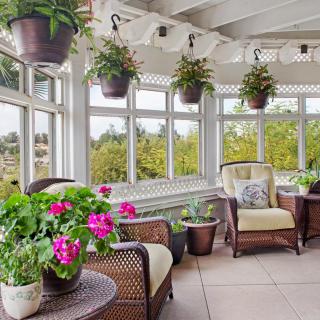 A bright and airy sunroom adorned with wicker furniture and vibrant plants.