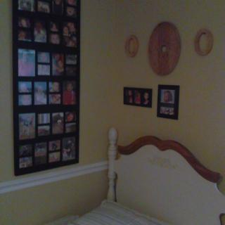 A cozy bedroom corner with yellow walls and various wall decorations.