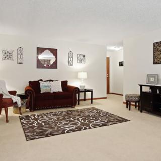A cozy living room with a burgundy sofa, patterned rug, and wall decorations.